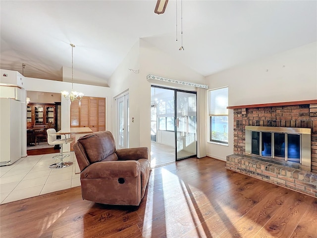 living room with a fireplace, hardwood / wood-style flooring, high vaulted ceiling, and a notable chandelier