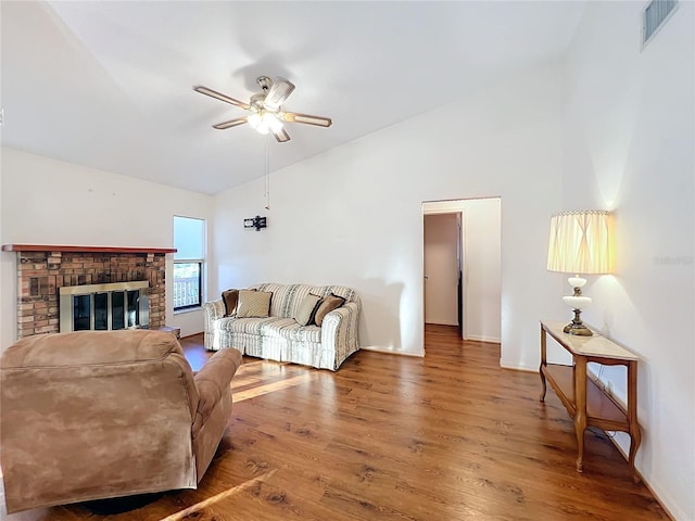 living room with ceiling fan, a fireplace, vaulted ceiling, and hardwood / wood-style flooring