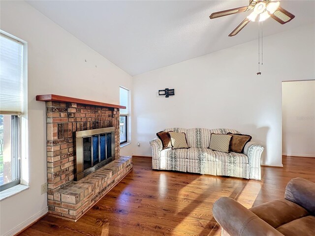 living room with a brick fireplace, ceiling fan, vaulted ceiling, and hardwood / wood-style flooring