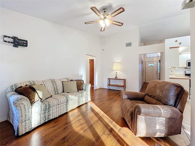 living room with a high ceiling, hardwood / wood-style flooring, and ceiling fan