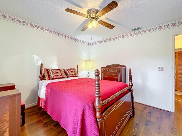 bedroom featuring ceiling fan, dark hardwood / wood-style flooring, and a textured ceiling