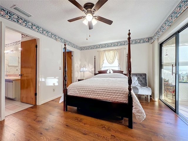 bedroom featuring access to outside, ensuite bath, ceiling fan, light wood-type flooring, and a textured ceiling