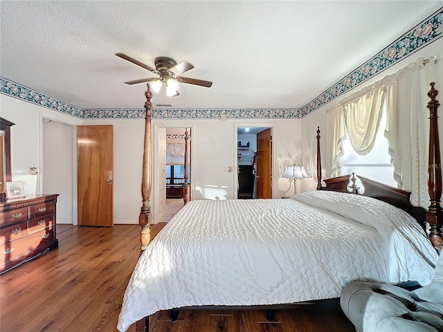 bedroom with a walk in closet, ceiling fan, a textured ceiling, wood-type flooring, and a closet