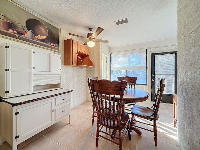 tiled dining space with a textured ceiling and ceiling fan