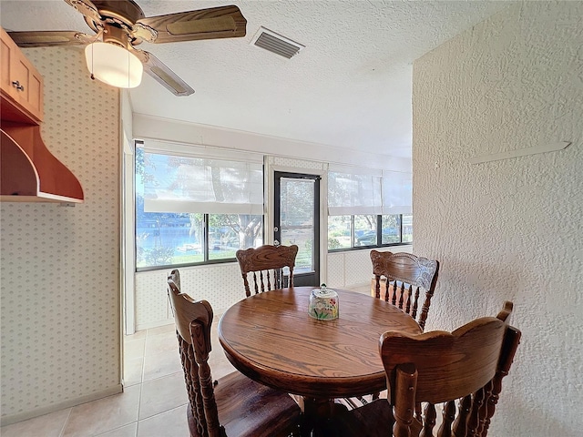 tiled dining space with ceiling fan and a textured ceiling