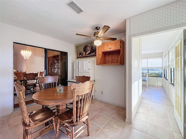 tiled dining space with a textured ceiling and ceiling fan with notable chandelier