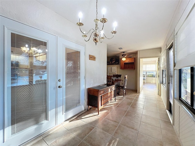 interior space with ceiling fan with notable chandelier and french doors