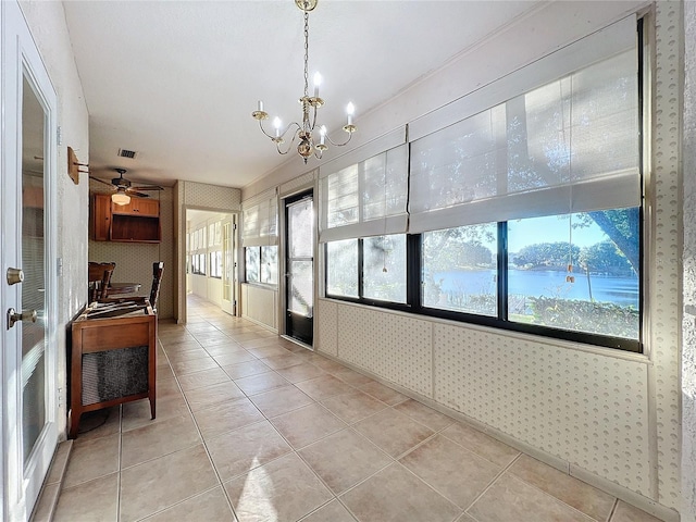 corridor featuring light tile patterned floors, a water view, and a notable chandelier