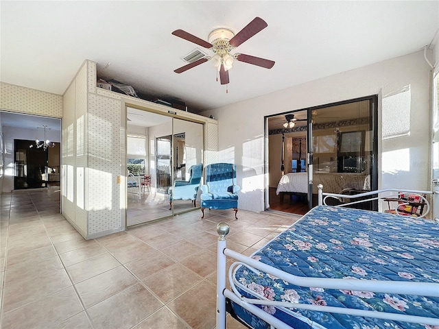 bedroom featuring tile patterned flooring, ceiling fan with notable chandelier, and a closet