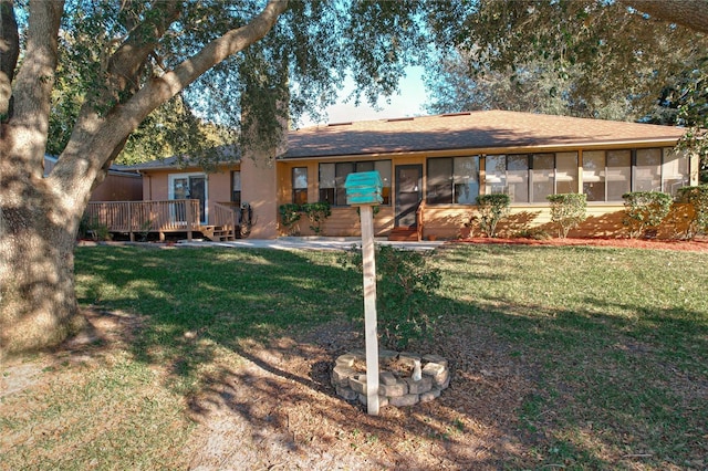 back of house with a yard, a sunroom, and a wooden deck