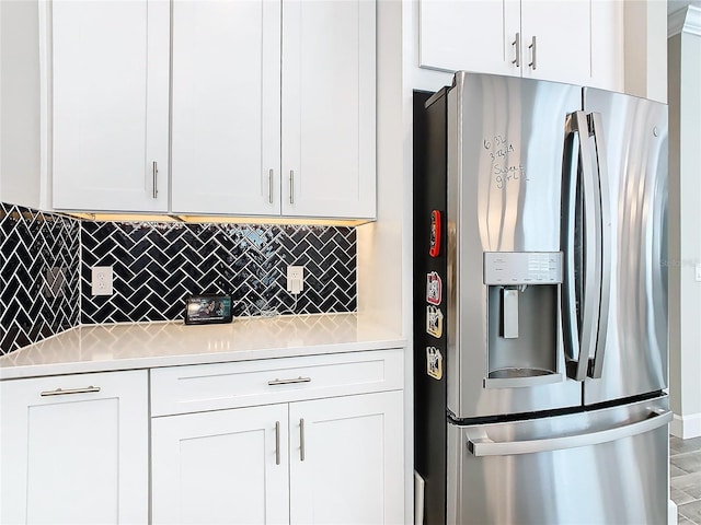 kitchen featuring white cabinetry, backsplash, and stainless steel fridge