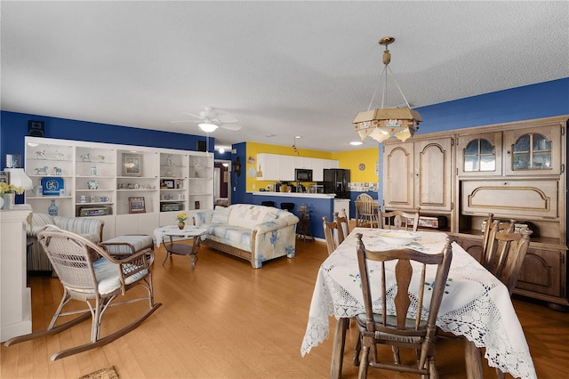 dining space featuring a textured ceiling, light wood-type flooring, and ceiling fan