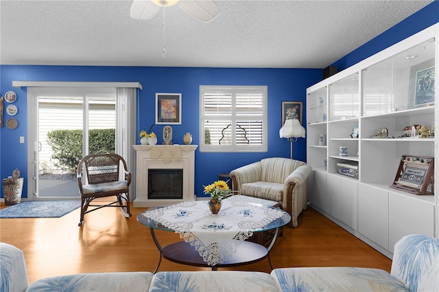 living room featuring ceiling fan, a textured ceiling, and hardwood / wood-style flooring