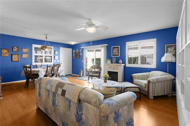 living room with ceiling fan, a textured ceiling, and hardwood / wood-style flooring