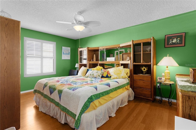 bedroom with a textured ceiling, light hardwood / wood-style flooring, and ceiling fan