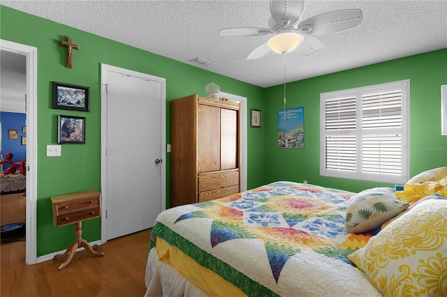 bedroom featuring hardwood / wood-style floors, ceiling fan, and a textured ceiling