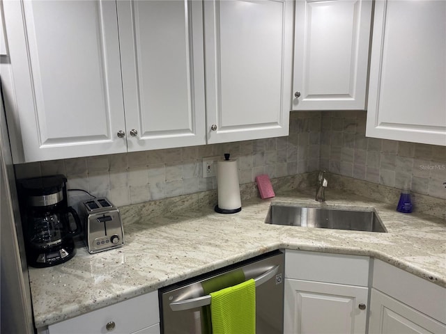 kitchen featuring backsplash, dishwasher, white cabinets, and sink