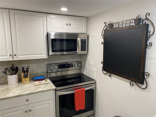 kitchen with white cabinetry, stainless steel appliances, and tasteful backsplash