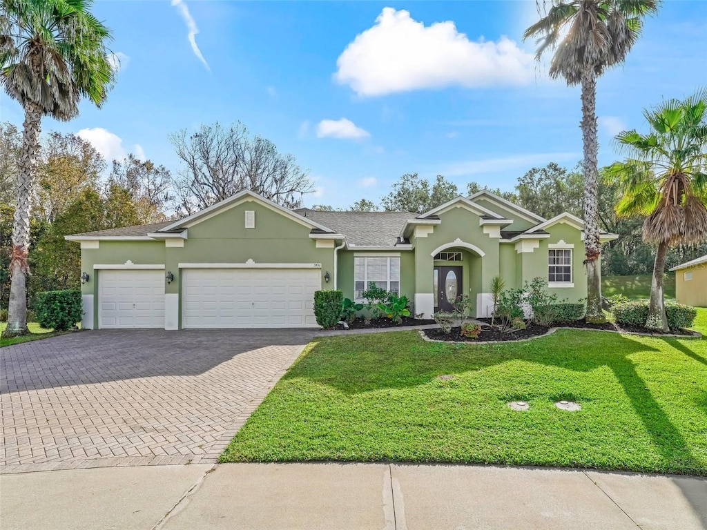 3556 Creek Run Ln, Eustis, FL 32736 - ranch-style home featuring stucco siding, a garage, decorative driveway, and a front lawn