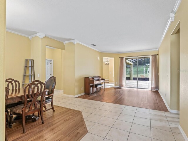 dining room featuring light hardwood / wood-style floors, crown molding, and a notable chandelier