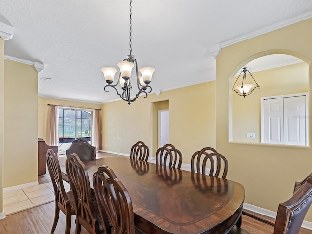 dining room featuring a textured ceiling, crown molding, a notable chandelier, and light wood-type flooring