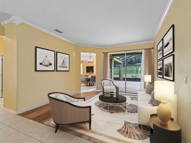 living room featuring a chandelier, a textured ceiling, light wood-type flooring, and crown molding