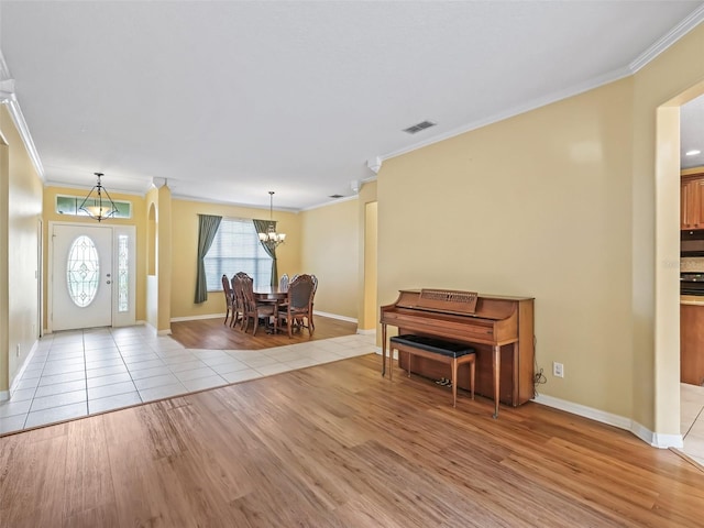 entryway featuring light wood-type flooring, an inviting chandelier, and ornamental molding