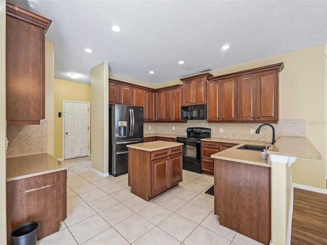 kitchen with kitchen peninsula, a kitchen breakfast bar, backsplash, sink, and black appliances