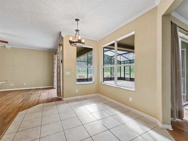 unfurnished dining area featuring a chandelier, ornamental molding, a textured ceiling, and light hardwood / wood-style flooring