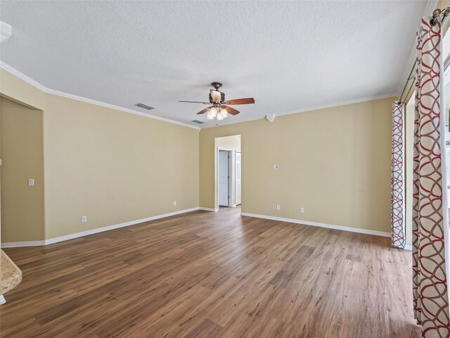 empty room featuring a textured ceiling, hardwood / wood-style flooring, and ornamental molding