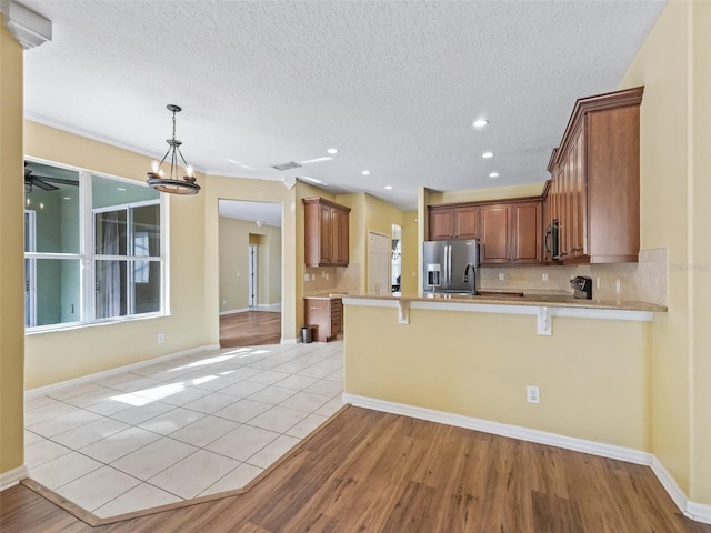 kitchen with tasteful backsplash, kitchen peninsula, light hardwood / wood-style floors, a breakfast bar area, and appliances with stainless steel finishes