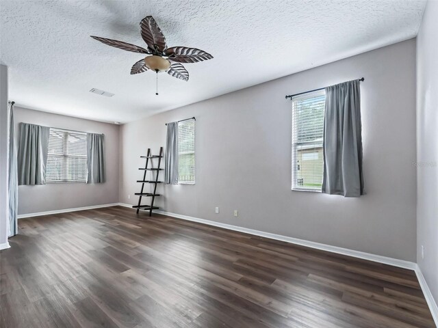 unfurnished room with ceiling fan, dark hardwood / wood-style flooring, a textured ceiling, and a wealth of natural light