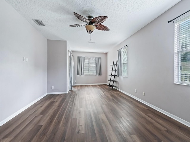 unfurnished room featuring a textured ceiling, plenty of natural light, and dark hardwood / wood-style floors