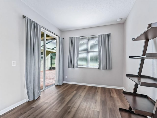 empty room featuring a textured ceiling and dark hardwood / wood-style floors