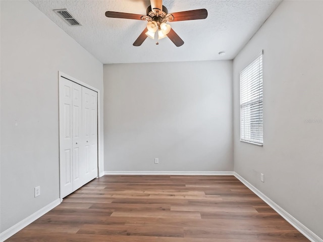 unfurnished bedroom featuring a closet, ceiling fan, hardwood / wood-style floors, and a textured ceiling