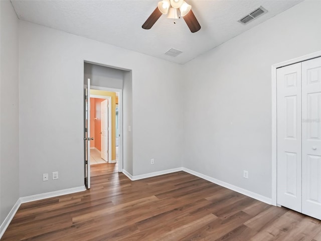 unfurnished bedroom featuring a textured ceiling, ceiling fan, and dark wood-type flooring