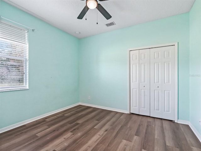 unfurnished bedroom featuring dark hardwood / wood-style floors, multiple windows, and ceiling fan