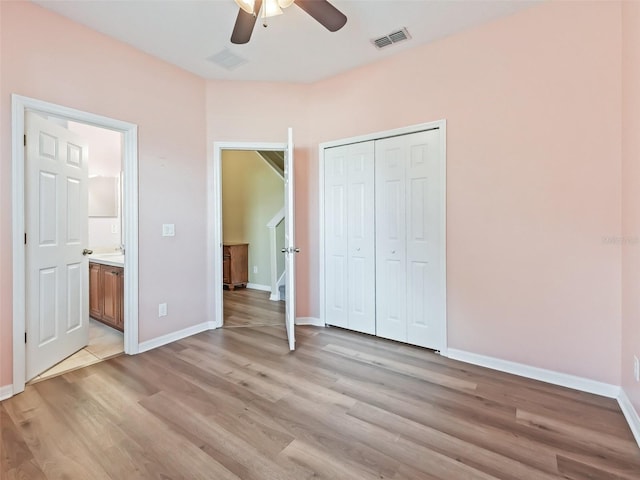 unfurnished bedroom with ensuite bath, ceiling fan, a closet, and light wood-type flooring