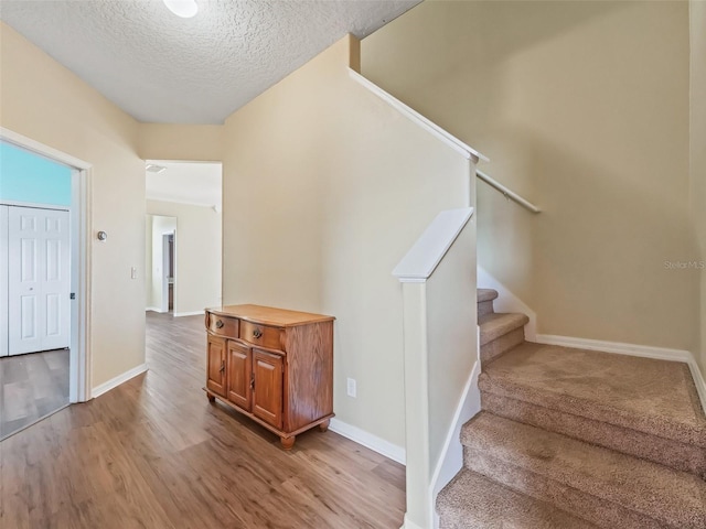 staircase featuring a textured ceiling and hardwood / wood-style flooring