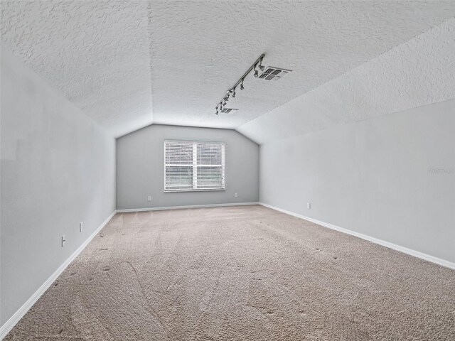 bonus room with carpet flooring, lofted ceiling, and a textured ceiling