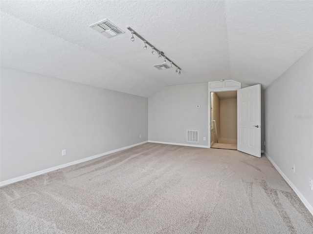 additional living space featuring a textured ceiling, light colored carpet, and vaulted ceiling