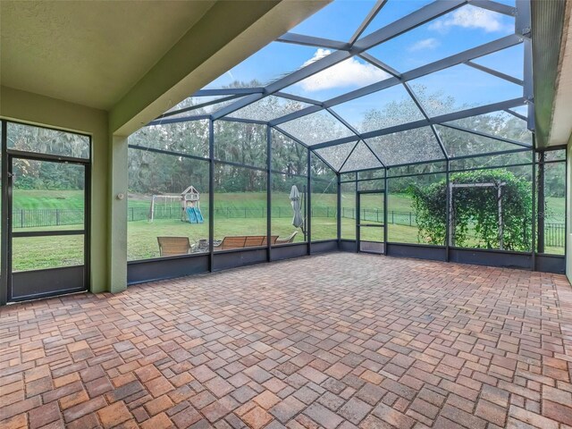 view of patio with a playground and glass enclosure