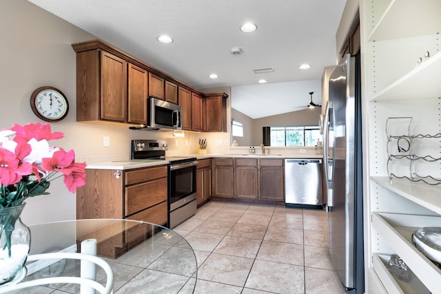 kitchen with ceiling fan, sink, lofted ceiling, light tile patterned flooring, and appliances with stainless steel finishes