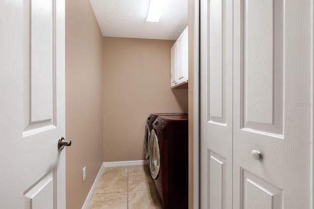 clothes washing area with washing machine and dryer, light tile patterned flooring, cabinets, and a textured ceiling