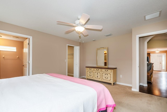 carpeted bedroom featuring ceiling fan, a spacious closet, multiple windows, and a closet