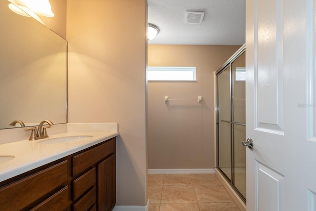 bathroom with tile patterned flooring, vanity, an enclosed shower, and a textured ceiling