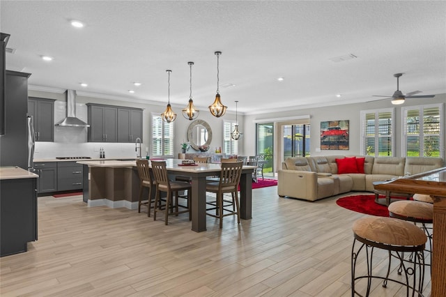 dining area featuring a textured ceiling, light hardwood / wood-style flooring, ceiling fan, and crown molding