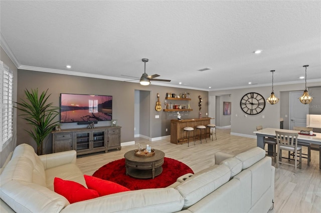 living room with crown molding, light hardwood / wood-style flooring, ceiling fan, and a textured ceiling