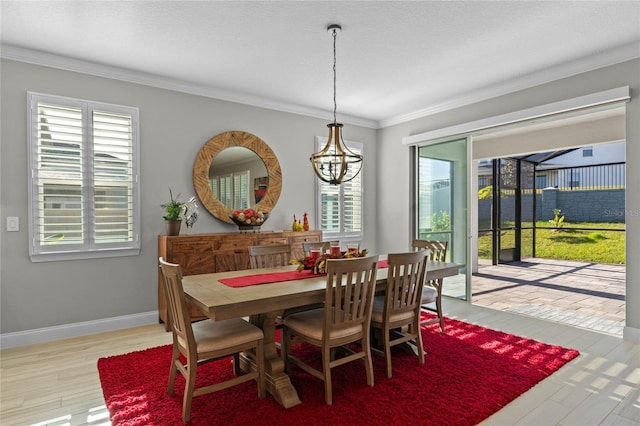 dining room with crown molding, light hardwood / wood-style flooring, and a notable chandelier