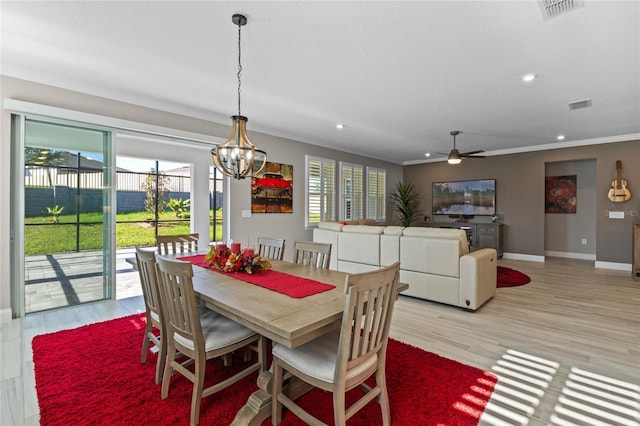 dining area with crown molding, light hardwood / wood-style flooring, and ceiling fan with notable chandelier